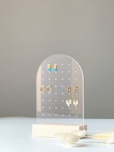 a clear acrylic display with earrings on it's sides and feathers in the foreground