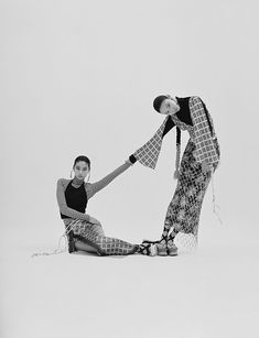 two women sitting on the ground with their legs wrapped around each other and one holding her leg