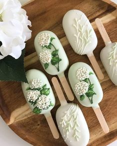 white flowers are on pops with wooden spoons