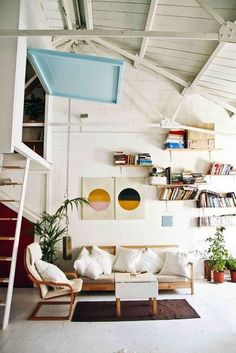 a living room filled with furniture and bookshelves next to a stair case full of books