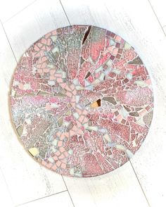 a pink and white mosaic plate sitting on top of a wooden floor