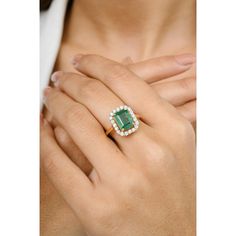 a woman wearing an emerald and diamond ring