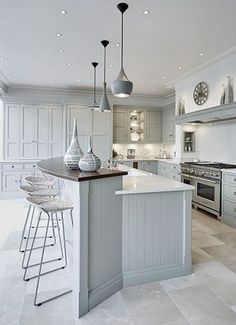 a large kitchen with an island in the middle and two stools at the end