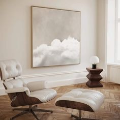 an empty chair and ottoman in front of a painting