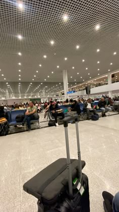 an airport filled with lots of people sitting in chairs and waiting for their bags to be picked up