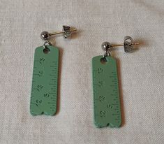 pair of green earrings with measuring tape on them