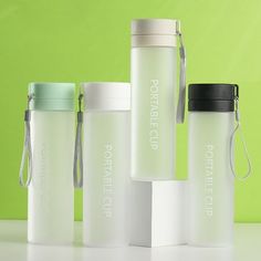 three white plastic bottles with black lids on a green background