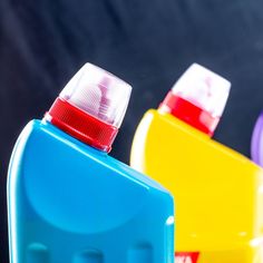 three different colored plastic containers sitting next to each other on a black surface, one with a red top and the other blue