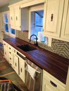 a kitchen with white cabinets and wood counter tops, an oven dishwasher in the center