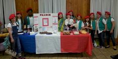 a group of people standing in front of a table with food and drinks on it