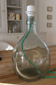 a glass bottle sitting on top of a wooden table next to a green cord in it