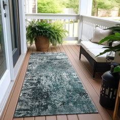 a large rug is on the porch near a couch and potted plant in front of an open door