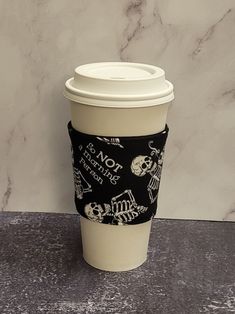 a coffee cup sleeve with skulls and bones on it sitting on a marble countertop