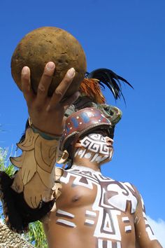 a man with painted face and body holding up a ball