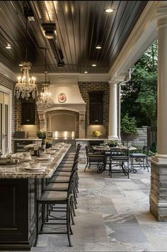 an outdoor kitchen and dining area is shown in this image, with chandeliers hanging from the ceiling