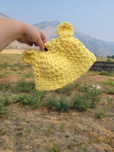 a hand holding up a yellow knitted bag