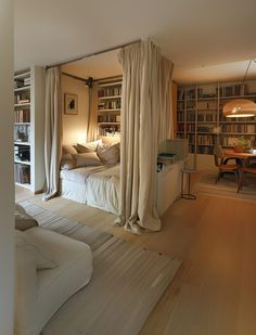 a bed sitting in the middle of a living room next to a book shelf