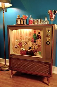 an old fashioned bar with liquor bottles and glasses on it's display case in front of a blue wall