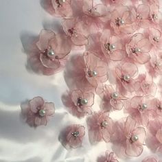 some pink flowers and pearls on a white cloth