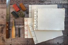 sewing supplies laid out on top of a wooden table with scissors, thread and paper