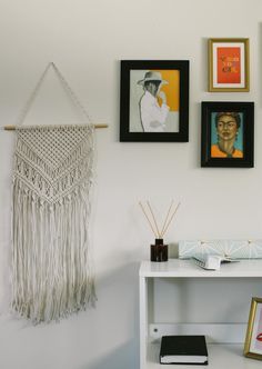 a white table topped with pictures next to a shelf filled with books and other items