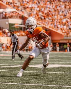 a football player running with the ball in his hand and an opposing team behind him