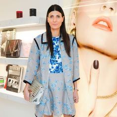 a woman standing in front of a wall with pictures on it and holding a purse