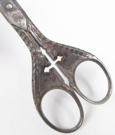 an old pair of scissors with a cross on the side and two holes in the middle