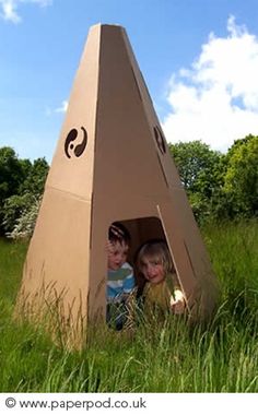 two children are sitting in a cardboard pyramid