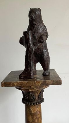 a statue of a bear sitting on top of a wooden table with a marble base