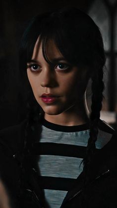 a close up of a person wearing a black and white striped shirt with braids