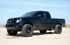 a black truck parked on top of a sandy beach