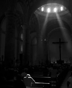 the sun shines brightly through the windows in a church as people sit on pews