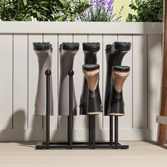 four black and brown vases sitting next to each other in front of a white fence