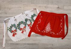 two red and white aprons with christmas decorations on them sitting on a wooden floor