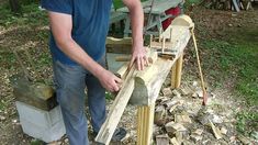 a man working on a wooden bench made out of logs and wood shavings