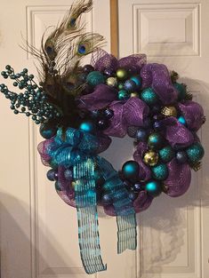 a purple wreath with blue and green ornaments hanging on the front door, decorated with peacock feathers