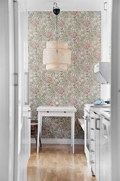 a white table sitting in the middle of a kitchen next to a wall with flowers on it