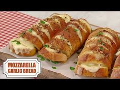 several pieces of bread with cheese and herbs on it sitting on a cutting board next to a checkered table cloth