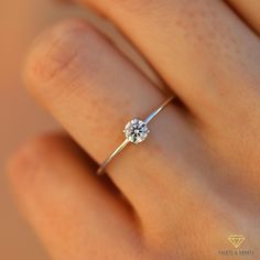 a woman's hand with a diamond ring on top of her finger, close up