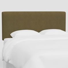 an upholstered headboard with white sheets and pillows