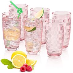 the glasses are lined up with lemons and raspberries