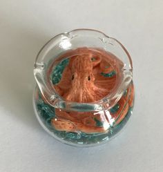 an orange octopus in a glass bowl on a white table top with water around it