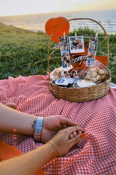 a person sitting on a blanket with a basket full of food next to the ocean