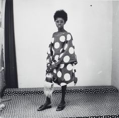 a black and white photo of a woman standing in front of a polka dot wall