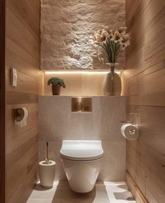 a white toilet sitting inside of a bathroom next to a wooden paneled wall and floor