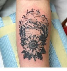 a sunflower tattoo on the arm that says life is about the mountains and trees