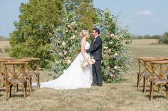 a bride and groom standing in front of an arch decorated with flowers at their wedding