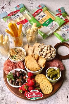 an assortment of snacks are arranged on a platter with crackers, cheeses, and strawberries