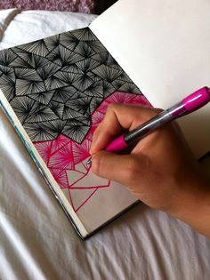 a person is writing on a notebook with a pink ballpoint pen in their hand